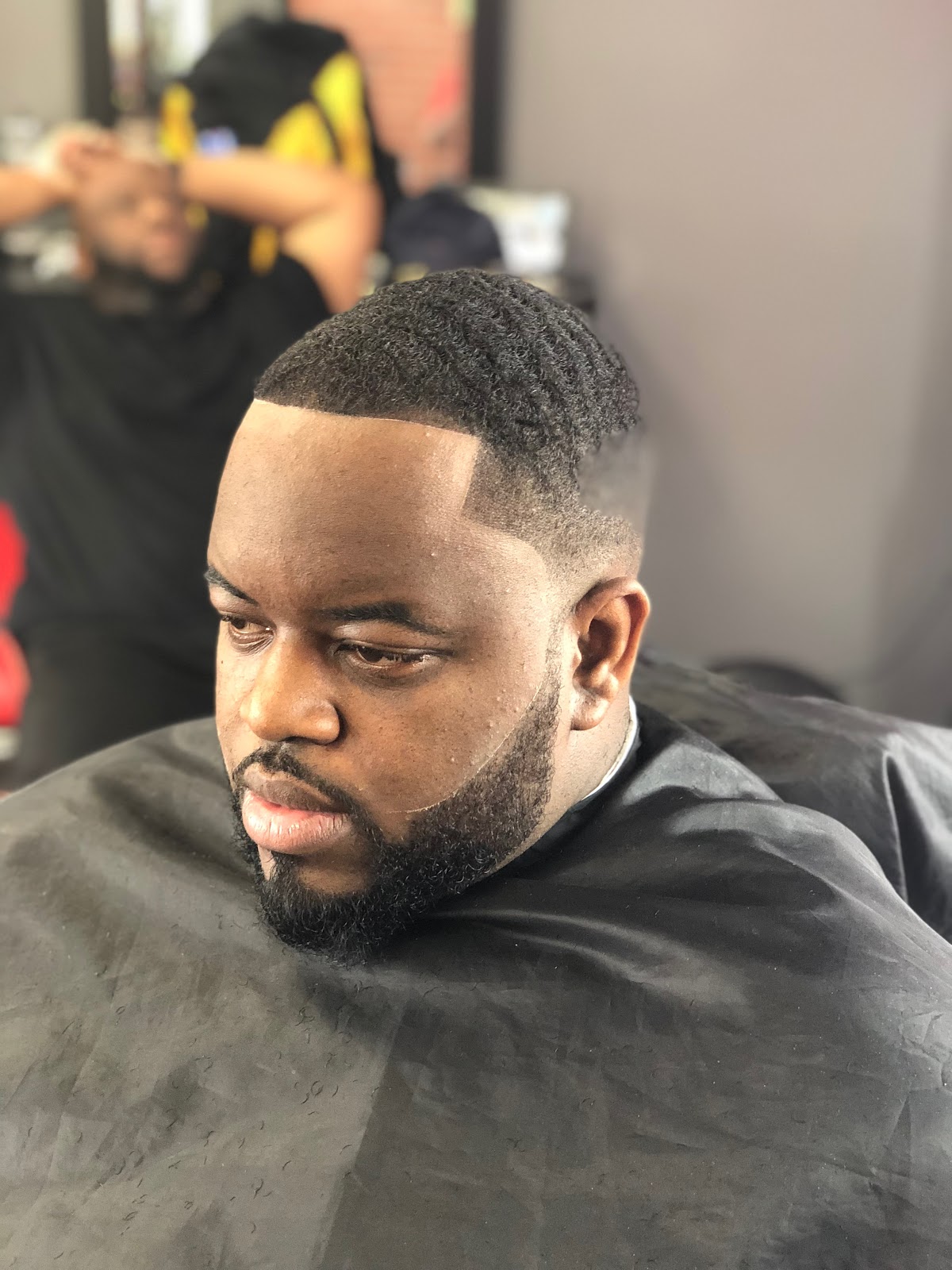 Clean low fade with a crisp line-up and shaped full beard